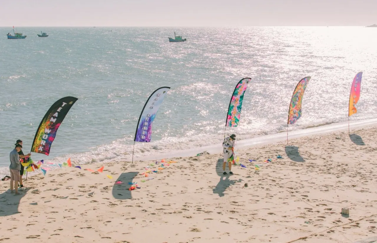 Feather flags on portable poles set up along a beach for an event